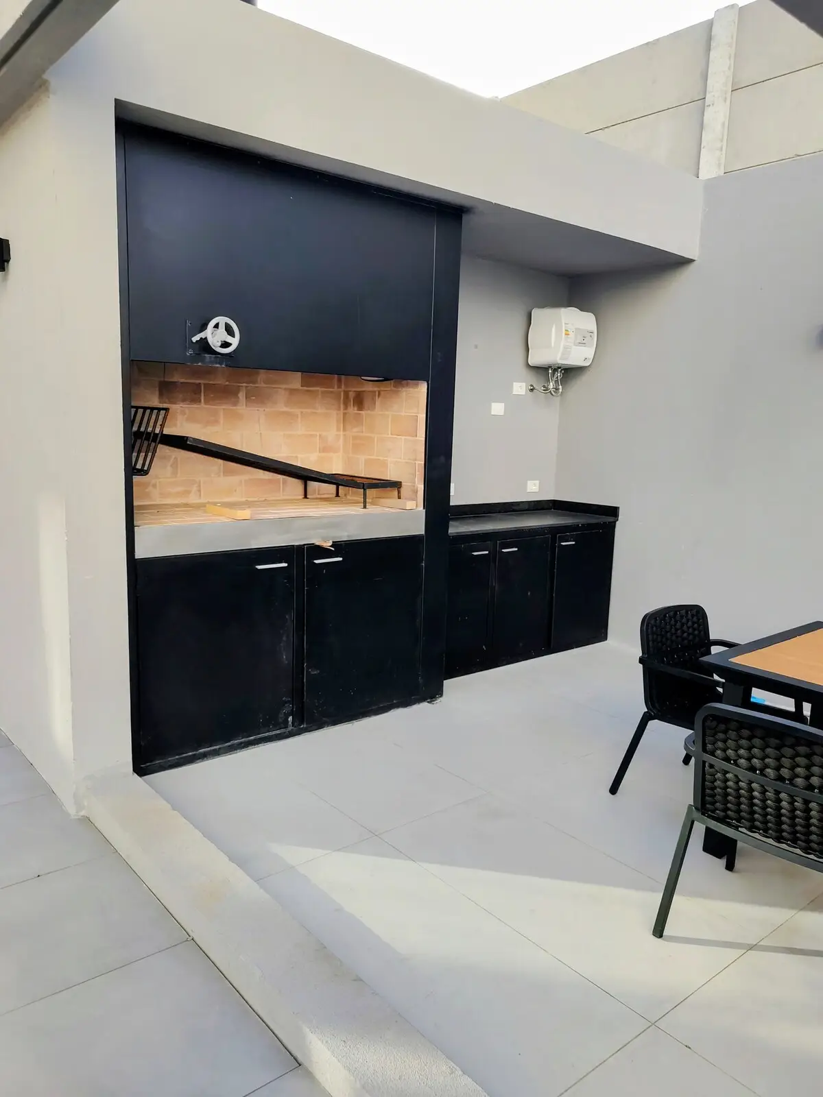 Zona de barbacoa común de diseño minimalista, con parrilla de hierro y amplios espacios de apoyo.
